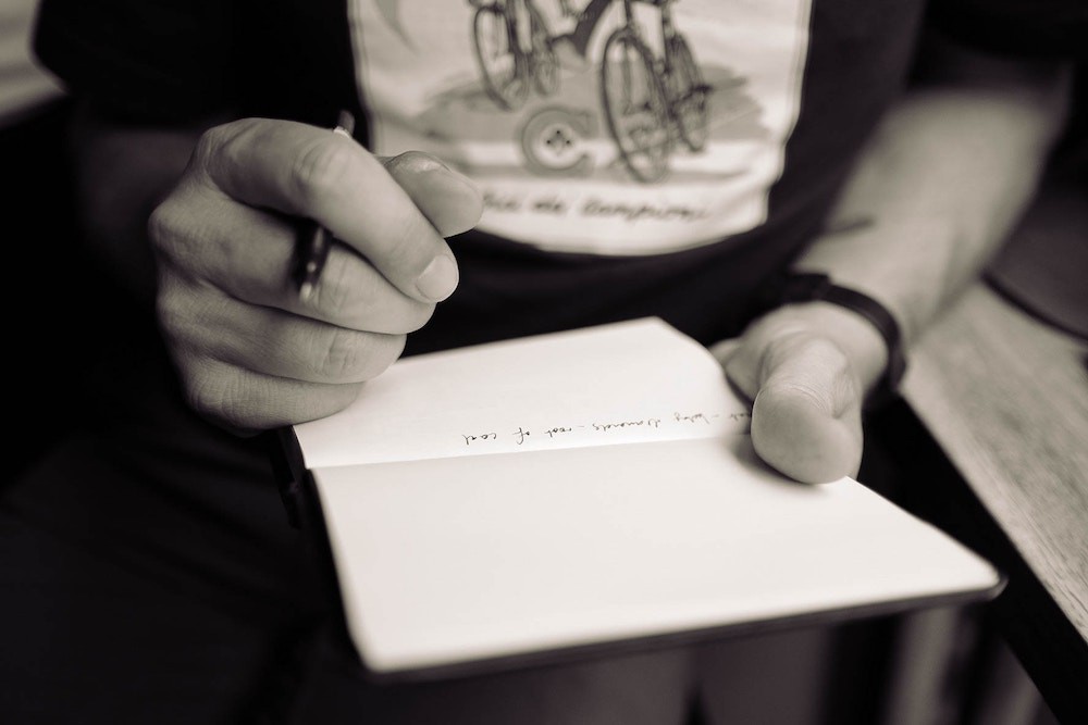 Young man writing down his ideas inside a plain notebook