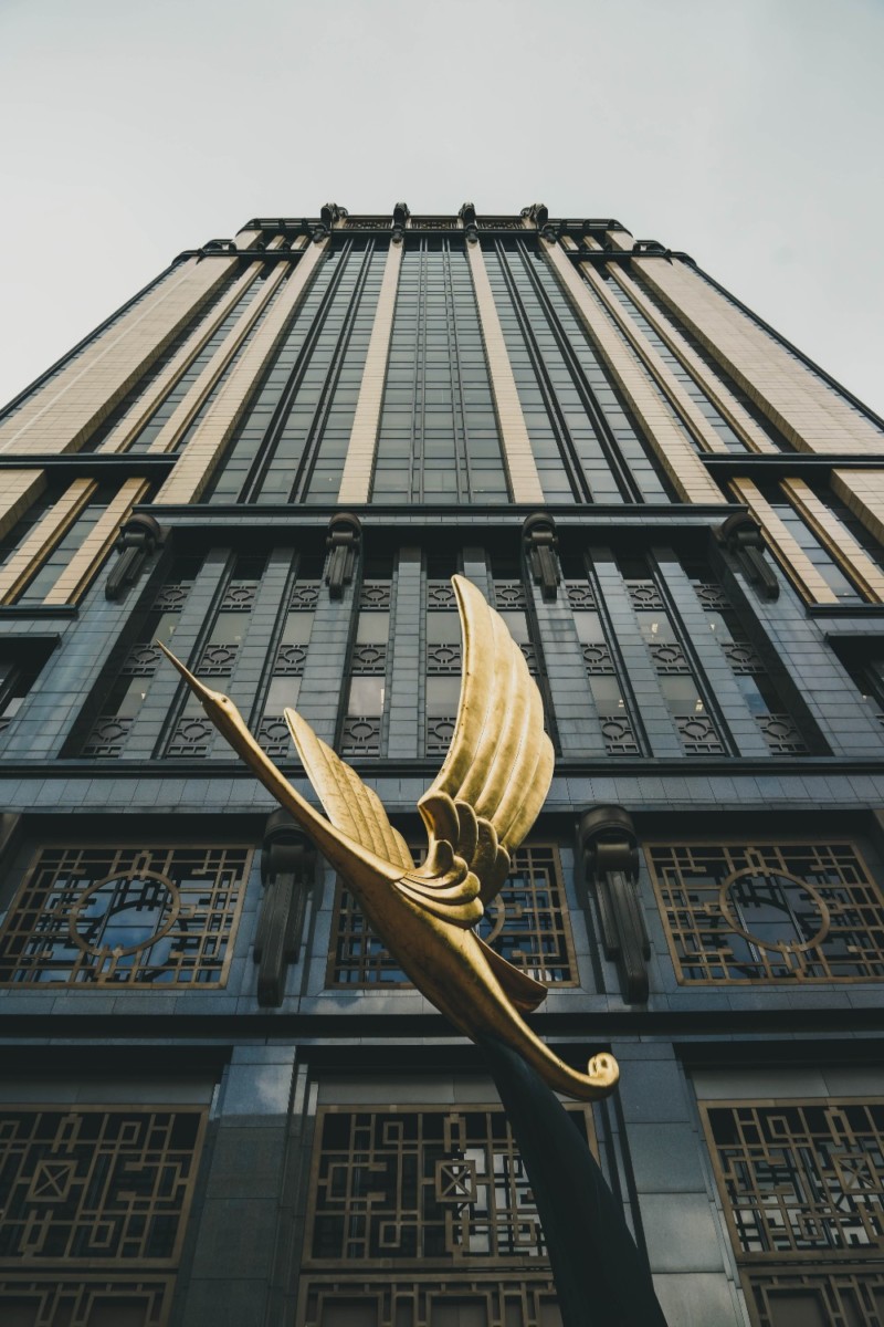 Golden Bird Statue in front of a Tall Dark Building