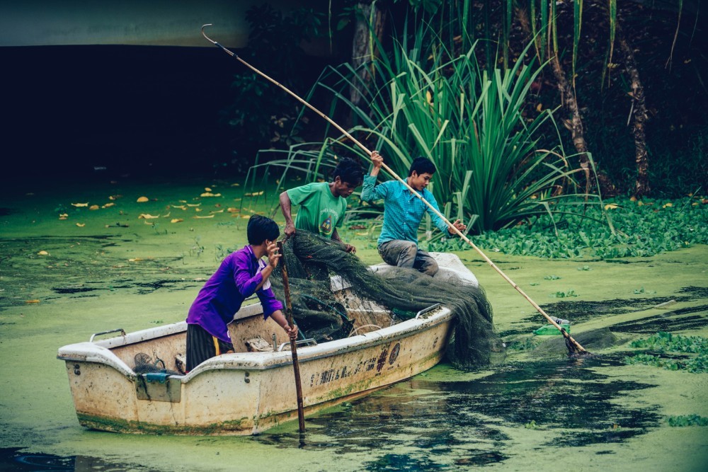 Three Men in a Rowboat Trying to Catch Fish in Cambodia