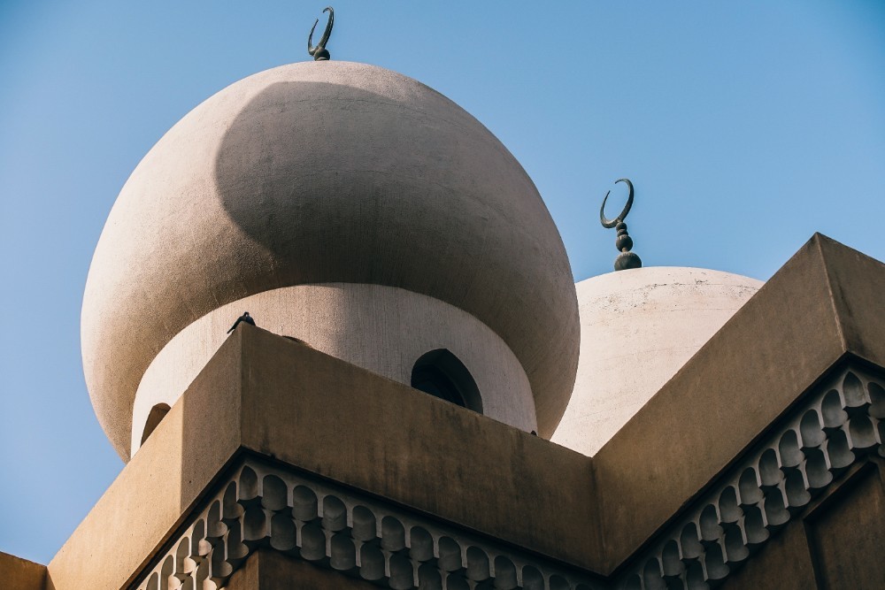 Two Pigeons Kissing While Sitting on top of a Mosque