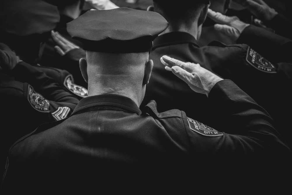 Police officer in a hat and uniform among other police officers giving honor