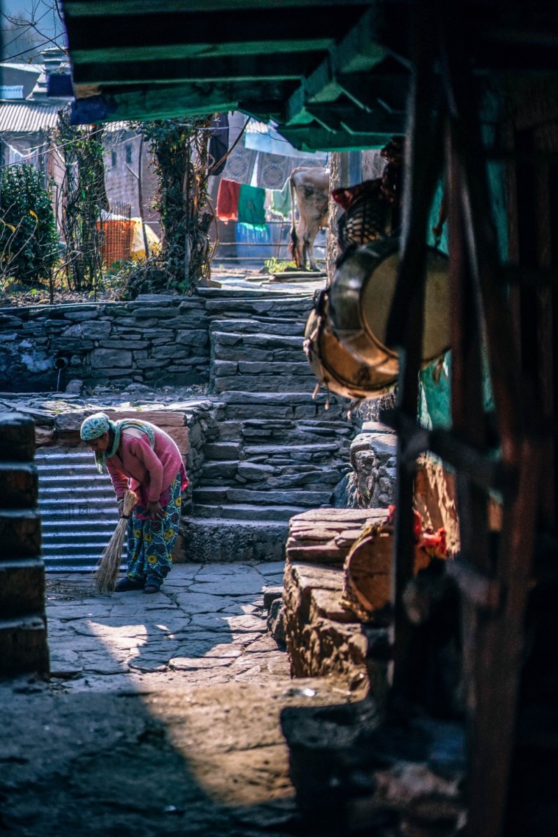 Woman cleaning the pathway to her house in Manali, India.