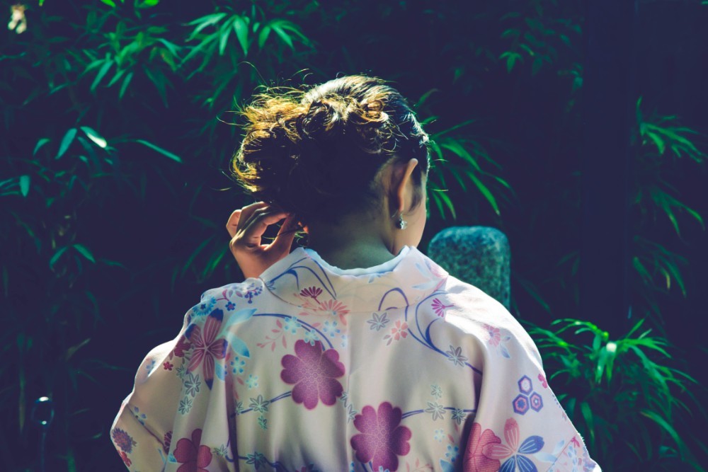 Japanese Woman Photographed in front of Dark Green Plants