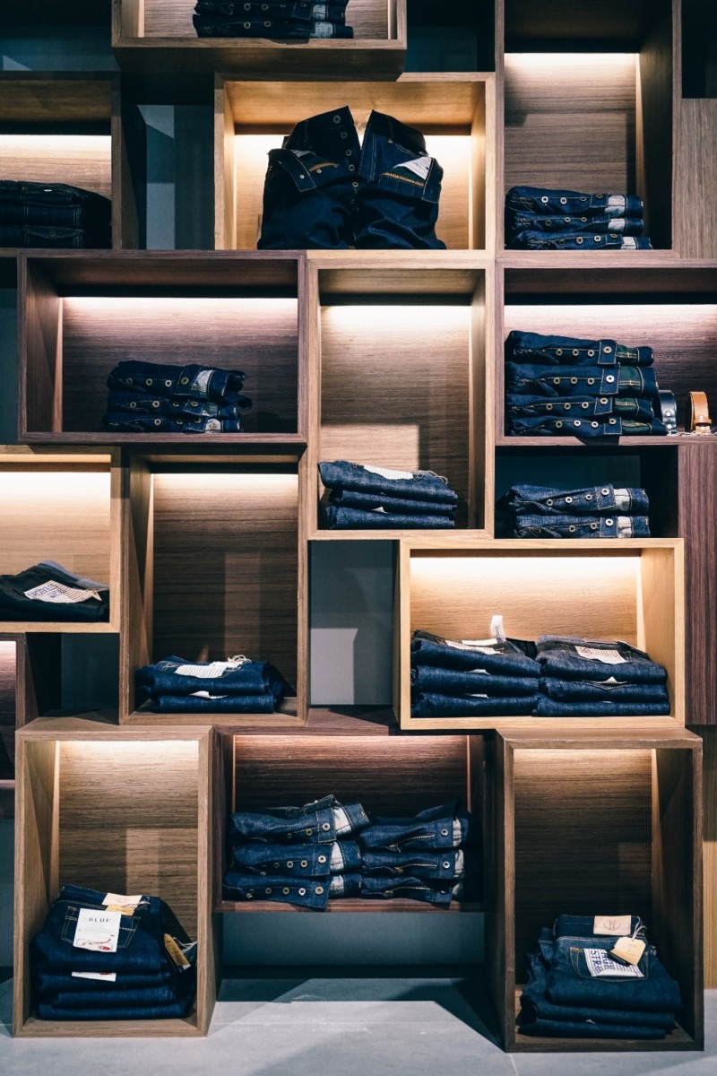 Contemporary wooden shelves with jeans displayed on them inside a mall in Bangkok.