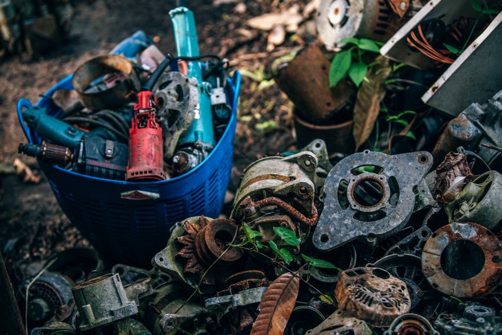 Old Rusty Metal Parts next to a Plastic Bucket full of Old Power Tools