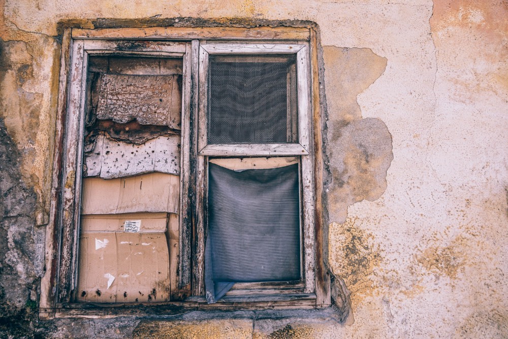 Old and Damaged Window with Cardboards instead of Glass