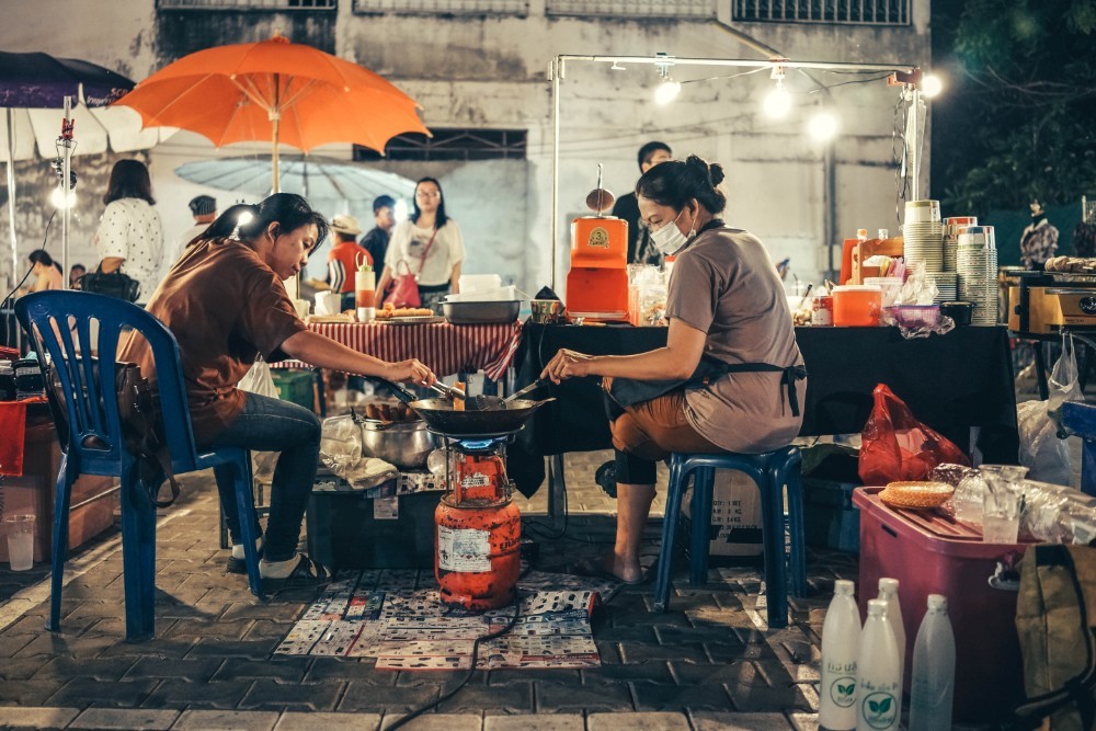 Two Thai Women Frying Food over a Gas Tank at a Night Market