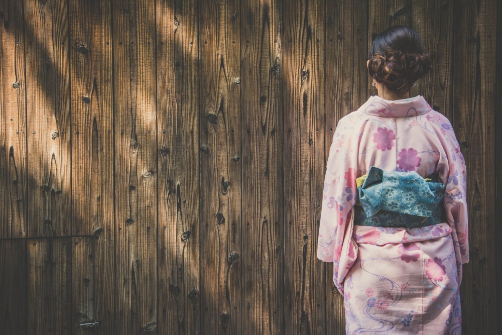 Woman dressed in a Japanese Kimono Standing in front of a Wooden Wall