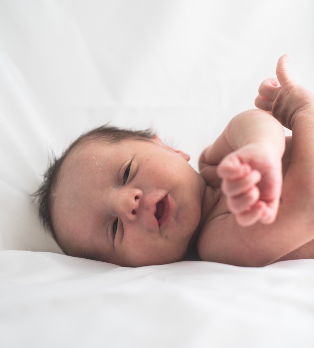 baby lying on white blanket