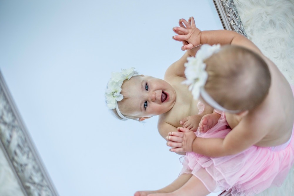 toddler facing mirror while smiling