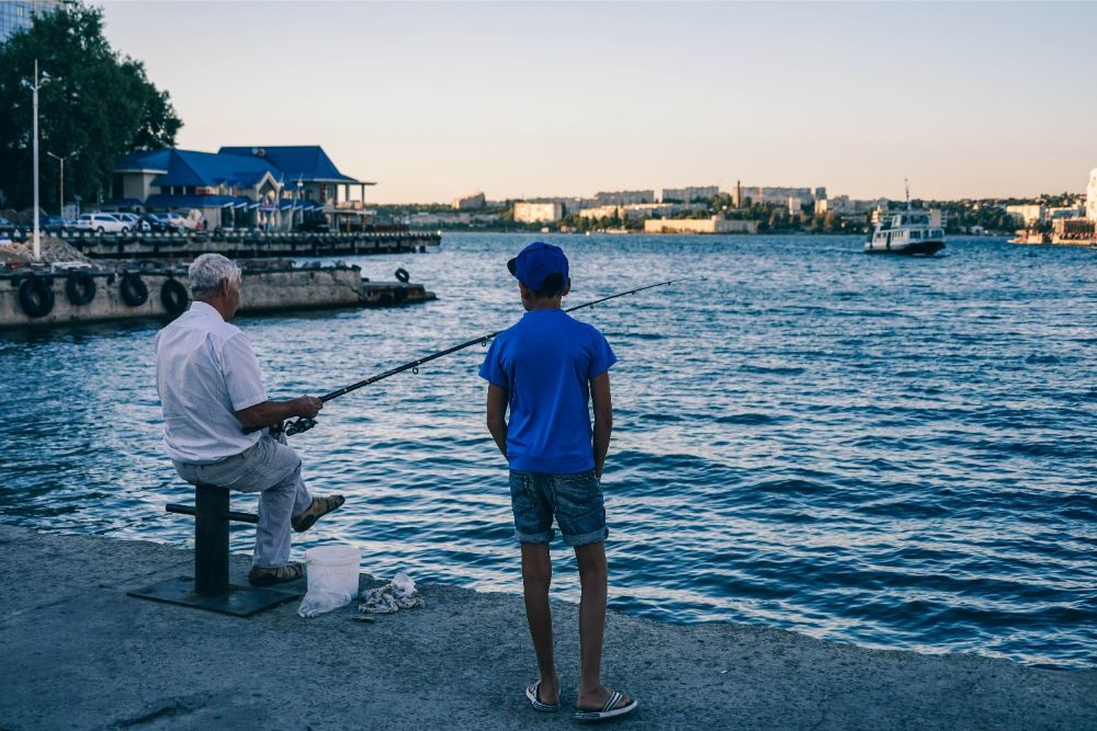 Old Man Teaching his Grandson to Catch Fish