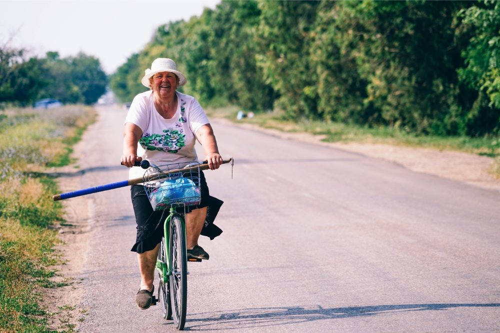 Old Woman Smiling at the Camera while Riding a Bicycle