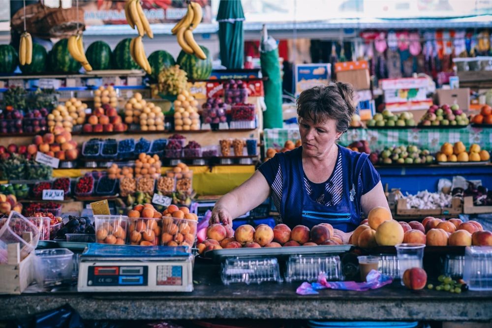 Woman Carefully Displaying Peaches at a Fruit Store