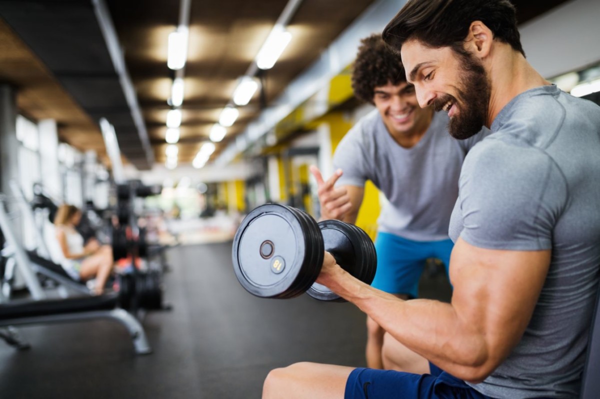 muscular bodybuilder guy doing exercises in gym ASEKGH