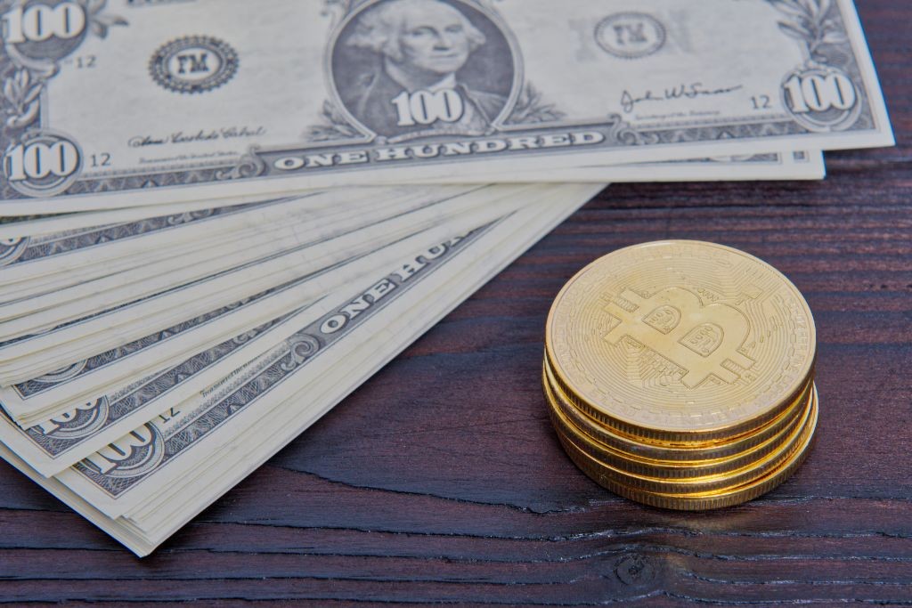 dollar banknotes and bitcoins on a table PRFKJEC