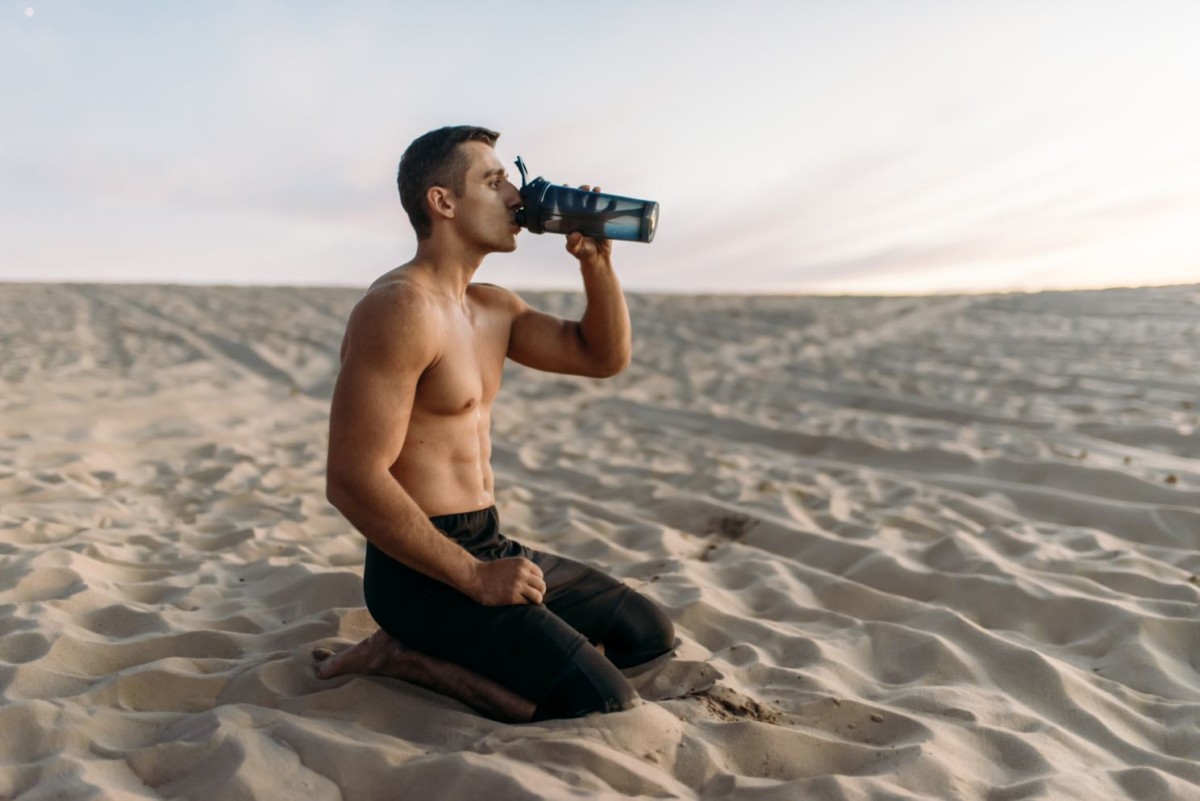 male athlete drinks water after workout in desert SP