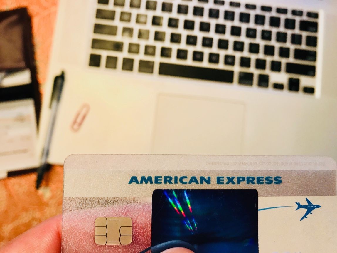 american express card with laptop checkbook and office supplies in the background on a table travel t YVPnNO