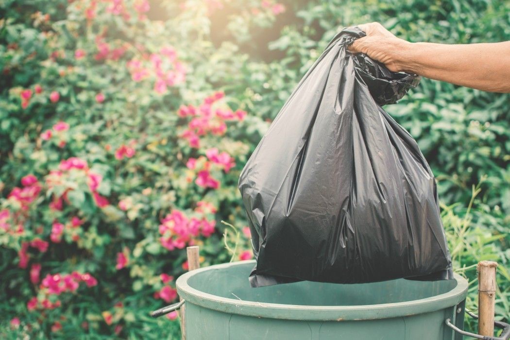 old hand holding plastic bag in to trash t Pywz