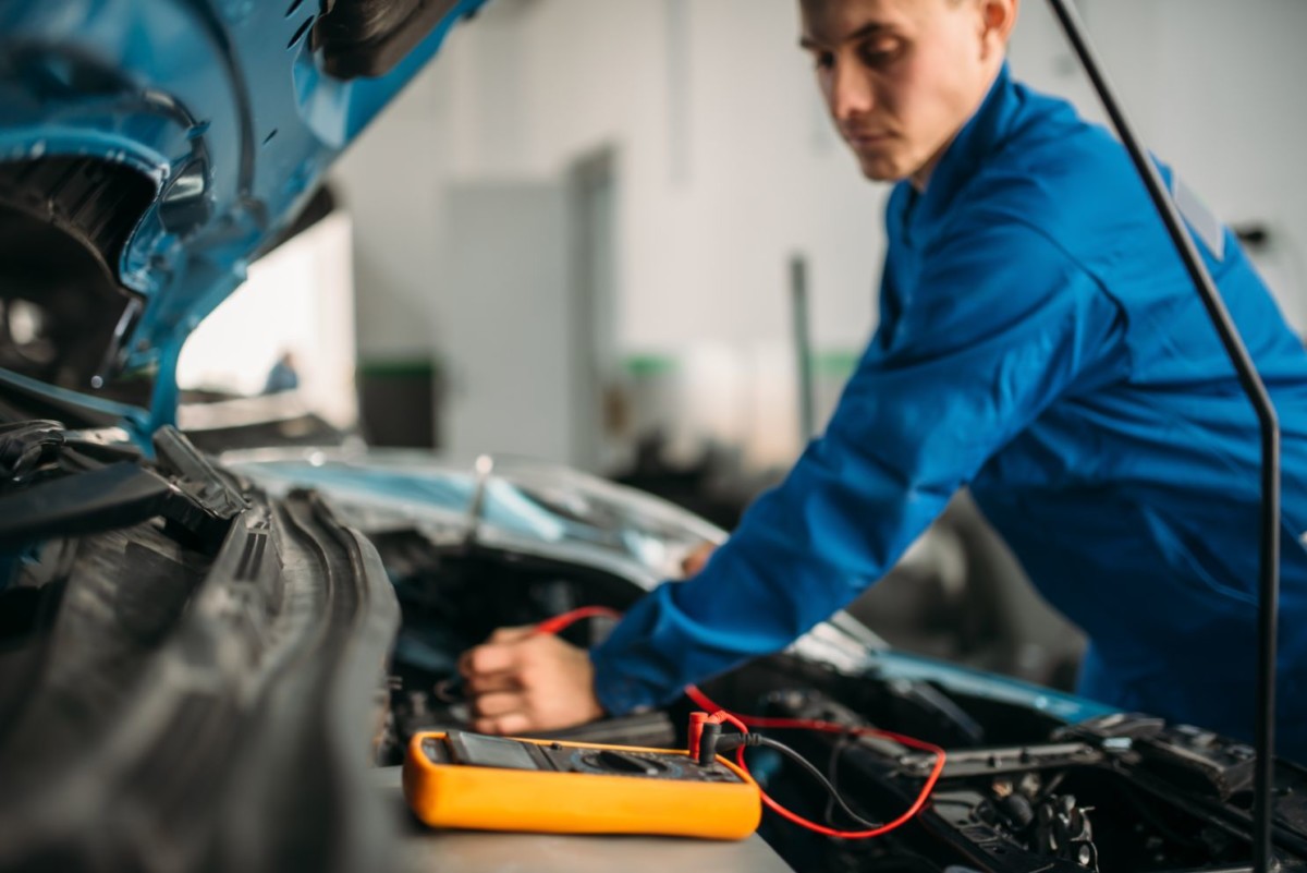 car repairman with multimeter battery inspection WHXLNC