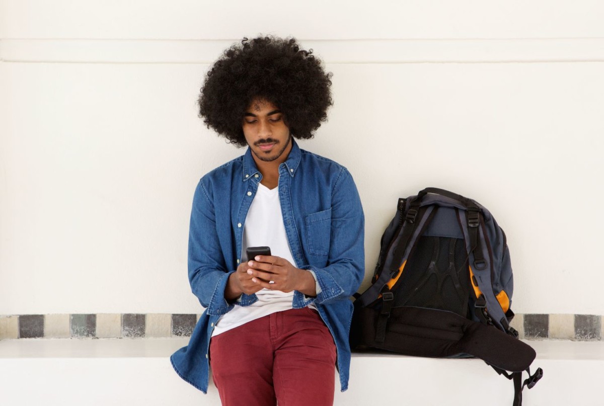 cool travel guy sitting with mobile phone and bag PLEFDD