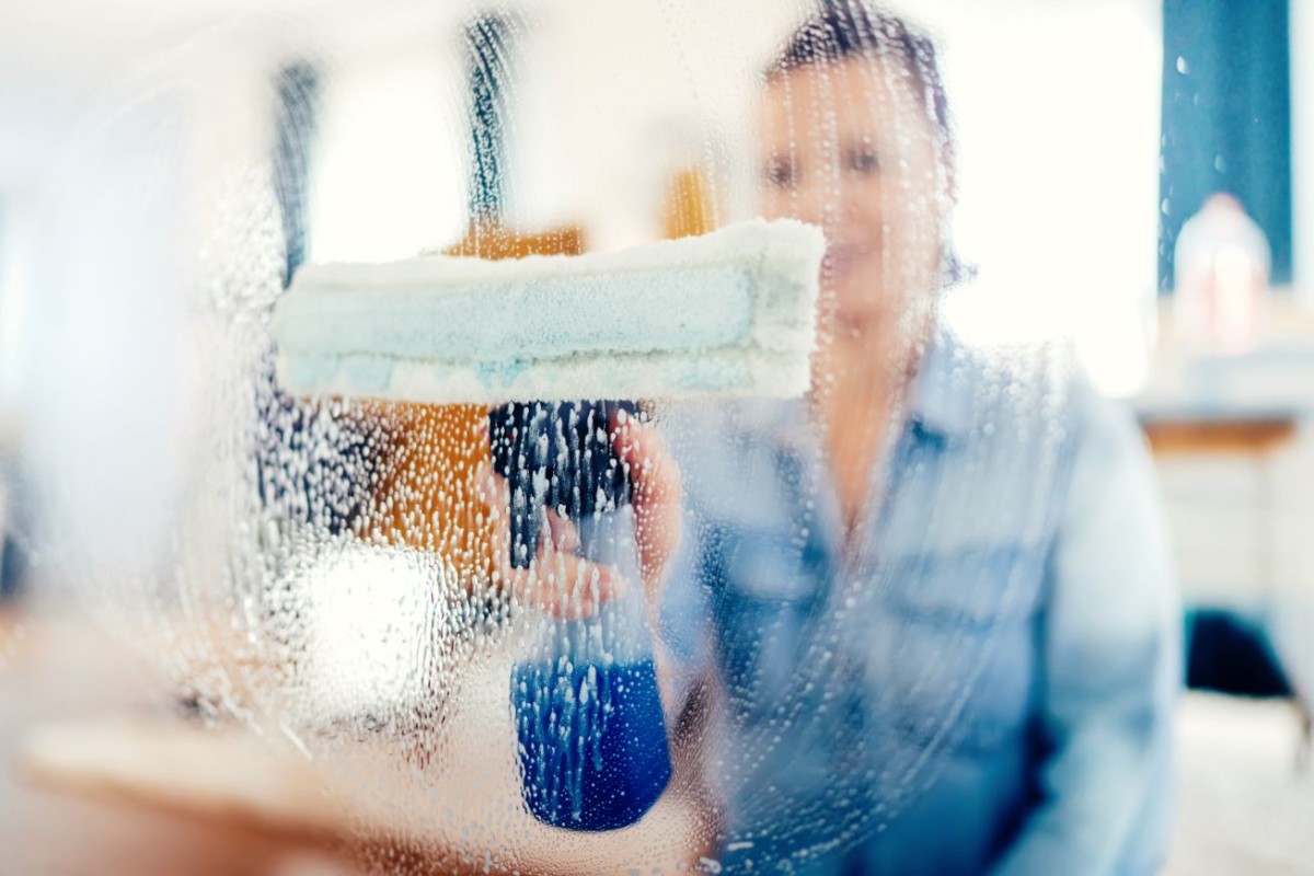 young woman using window cleaner and doing chores PKFV