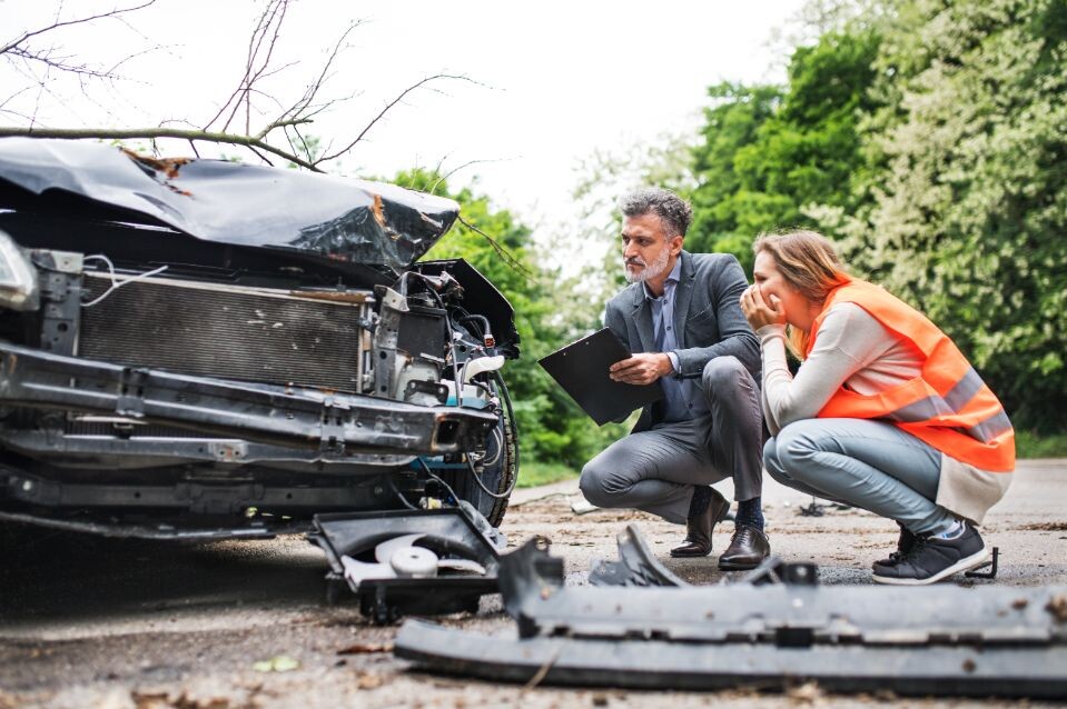 an insurance agent and a woman driver looking at t FKEGV