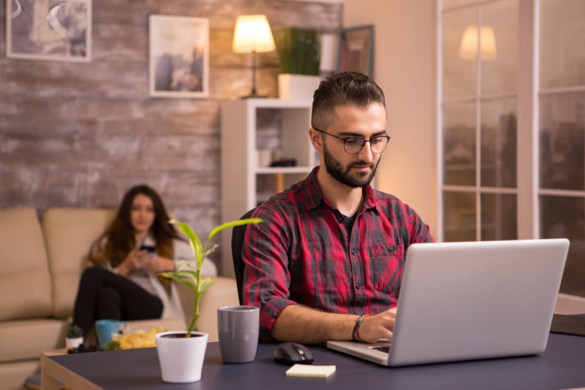 bearded freelancer working on laptop in living roo LFPYN