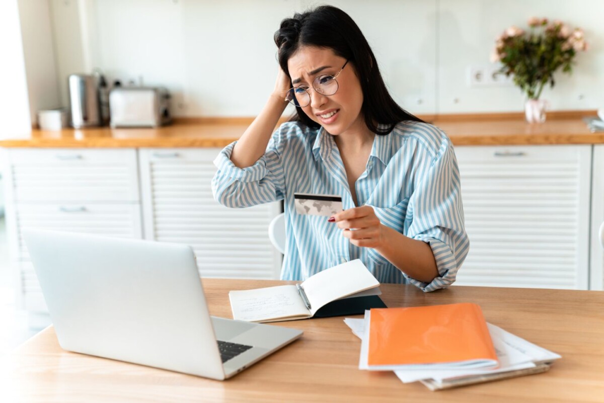 confused brunette young woman holding credit card JNFWBG