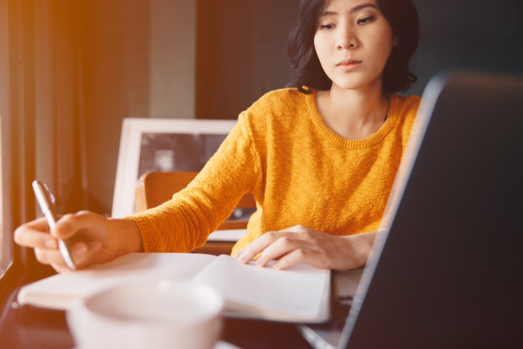 young business woman in yellow dress sitting at table in cafe and writing in notebook t PyoQr