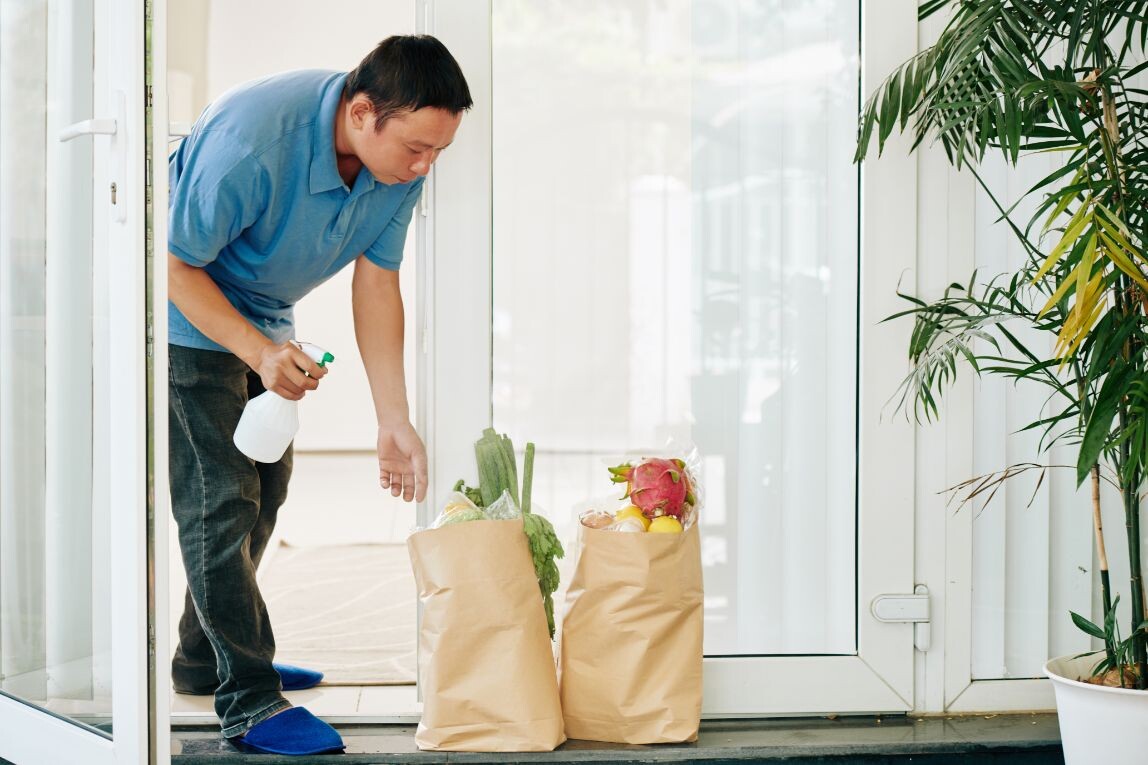 man spraying delivered grocery packages tvekk