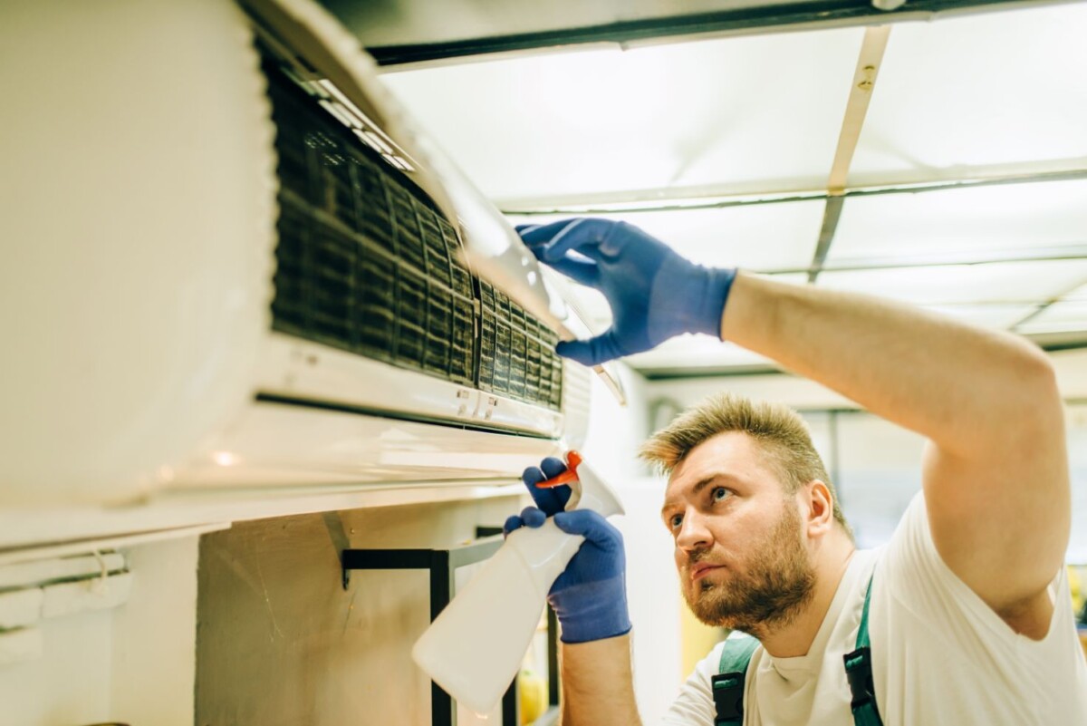 repairman in uniform cleans the air conditioner zhesw