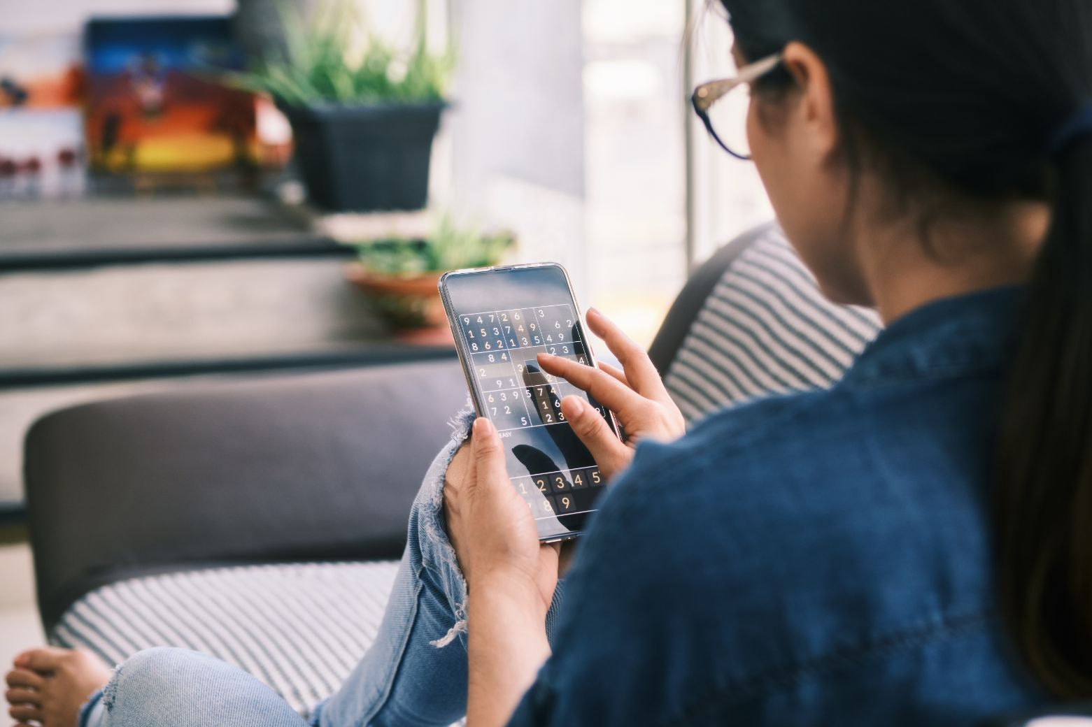 young woman playing sudoku game with app on phone buhtdzs