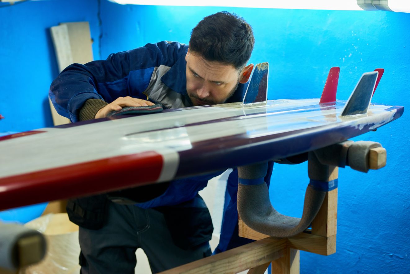 handsome man polishing custom surfing board JHRDAUG