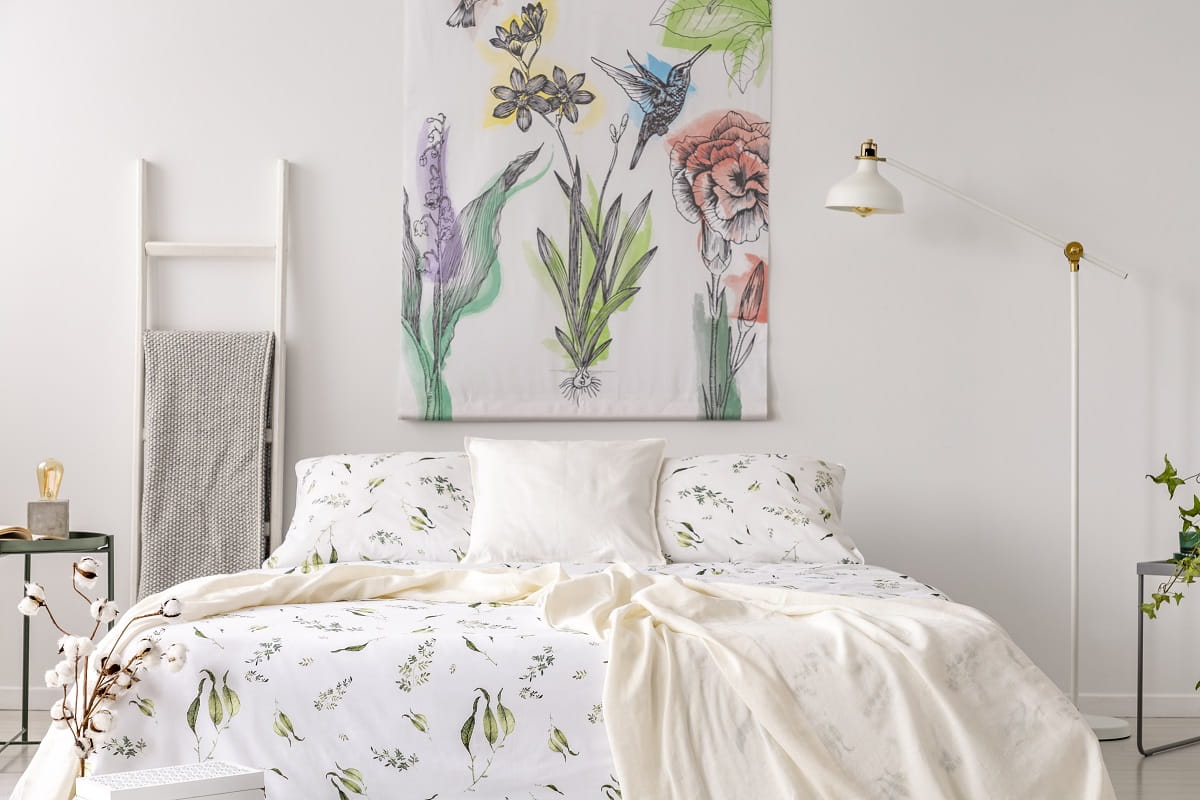 a pastel bedroom interior with a bed dressed in green plants pat