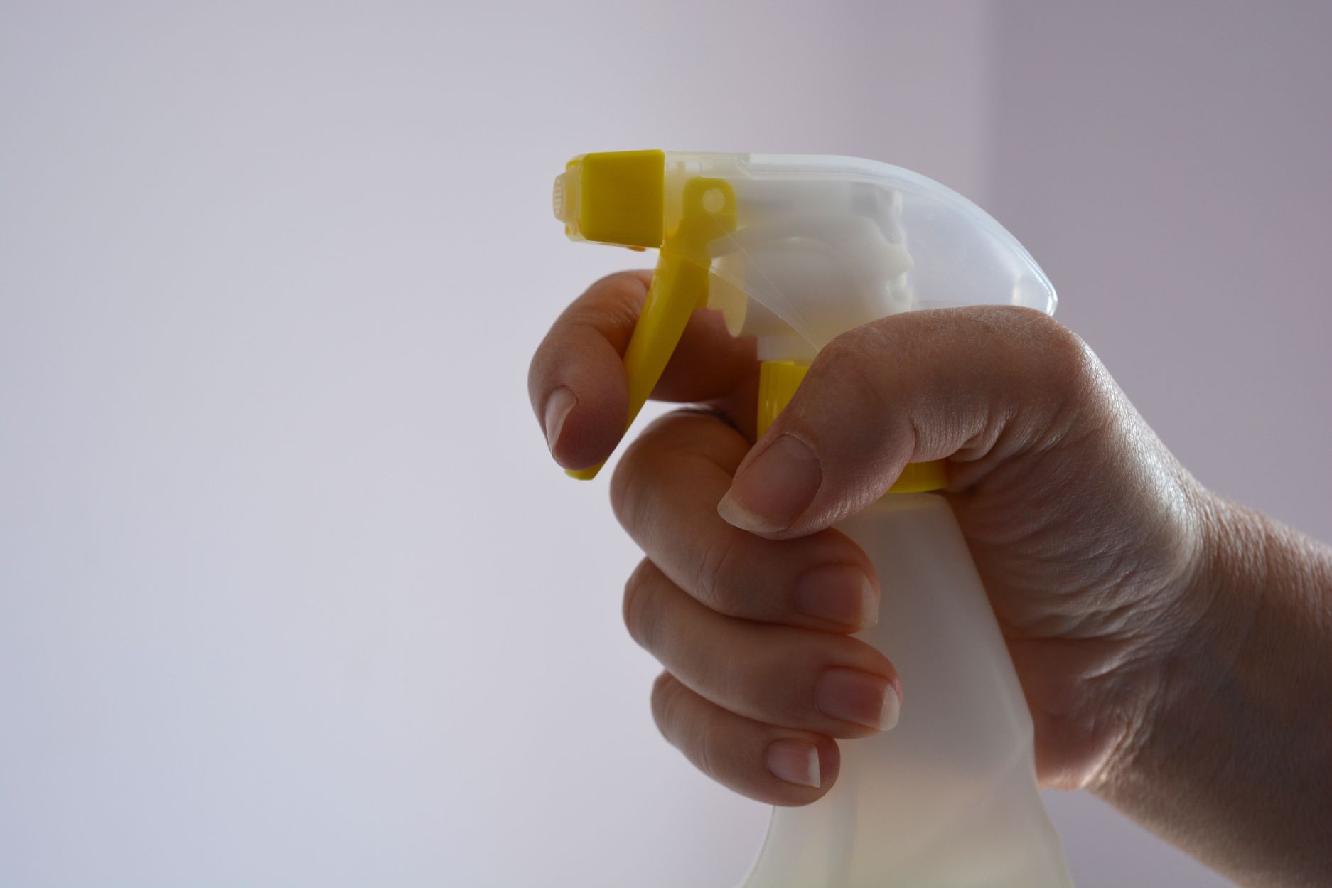 gloved hand holding a plastic spray bottle for liq ZTPB