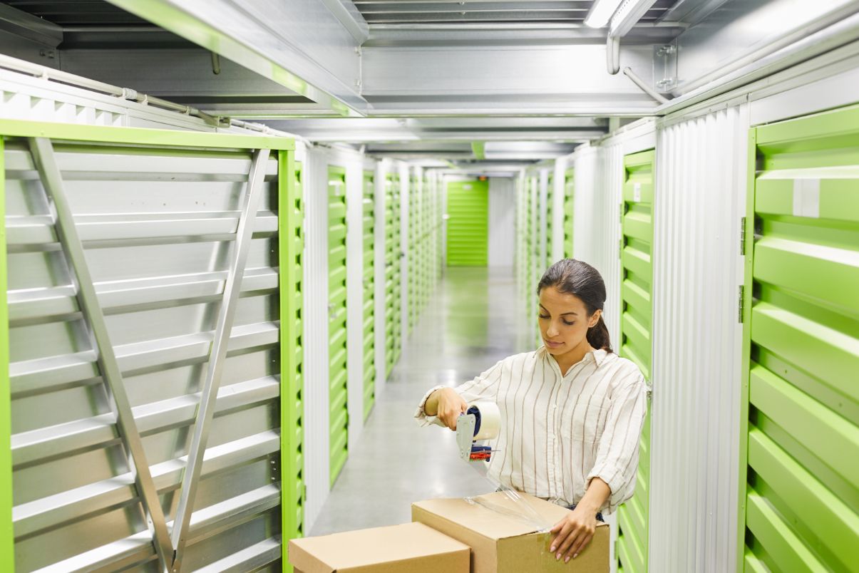 portrait of woman packing boxes in storage unit GBMXN