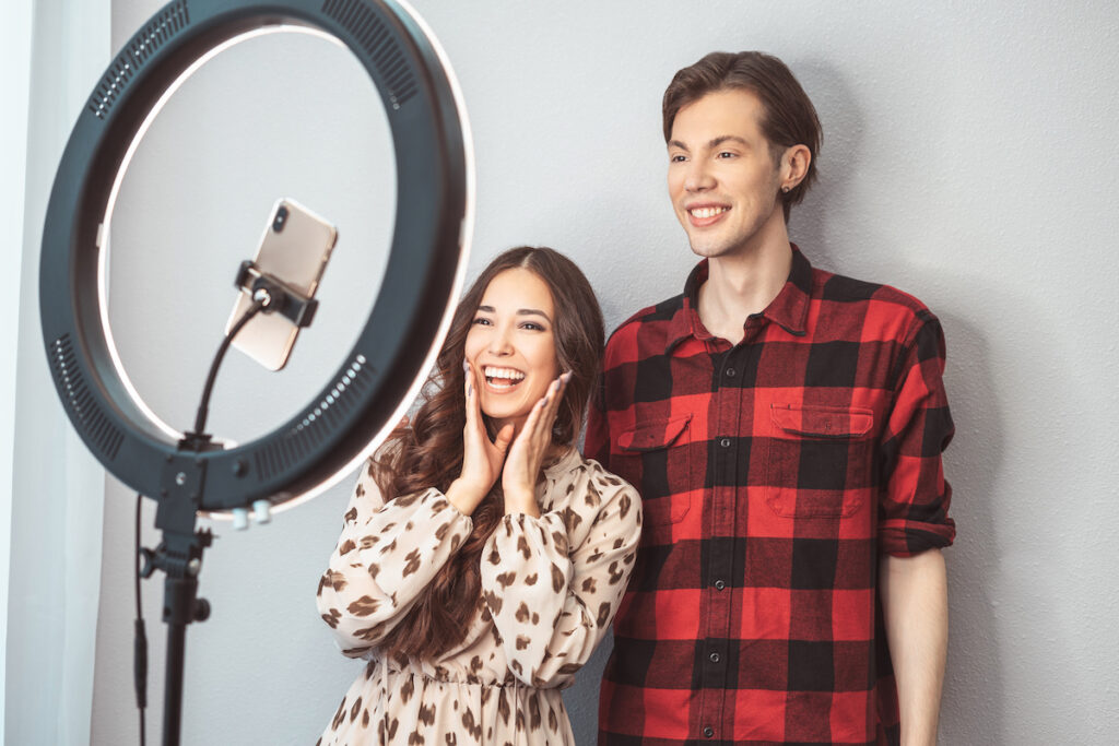 young couple of beauty bloggers hair stylist hairdresser and model with hair style shoot on a mobile phone with ring lamp