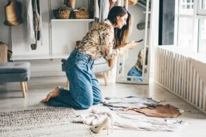 woman holds smartphone and makes photos of clothes to sellvia internet