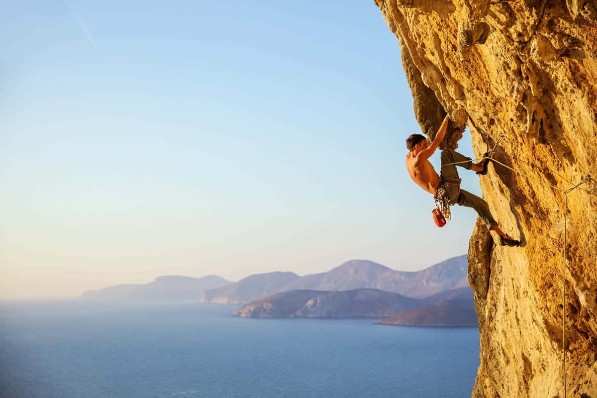 Young man struggling to climb challenging route on cliff