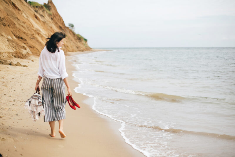 Happy boho woman relaxing at sea, enjoying walk on tropical island.