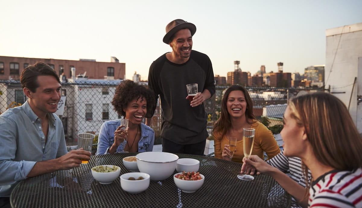 Six-adult-friends-laughing-at-a-table-on-a-rooftop