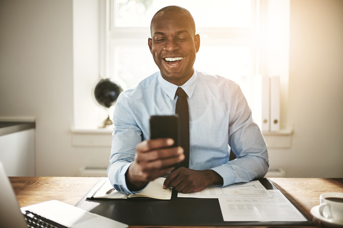 Smiling-young-businessman-laughing-at-a-cellphone-message