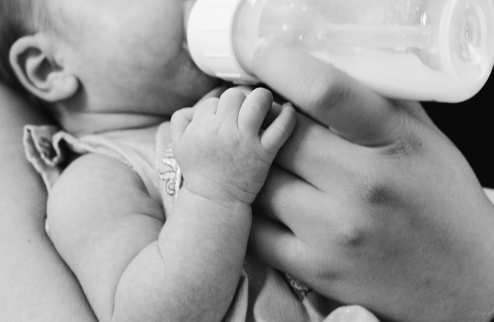 grayscale photo of baby feeding